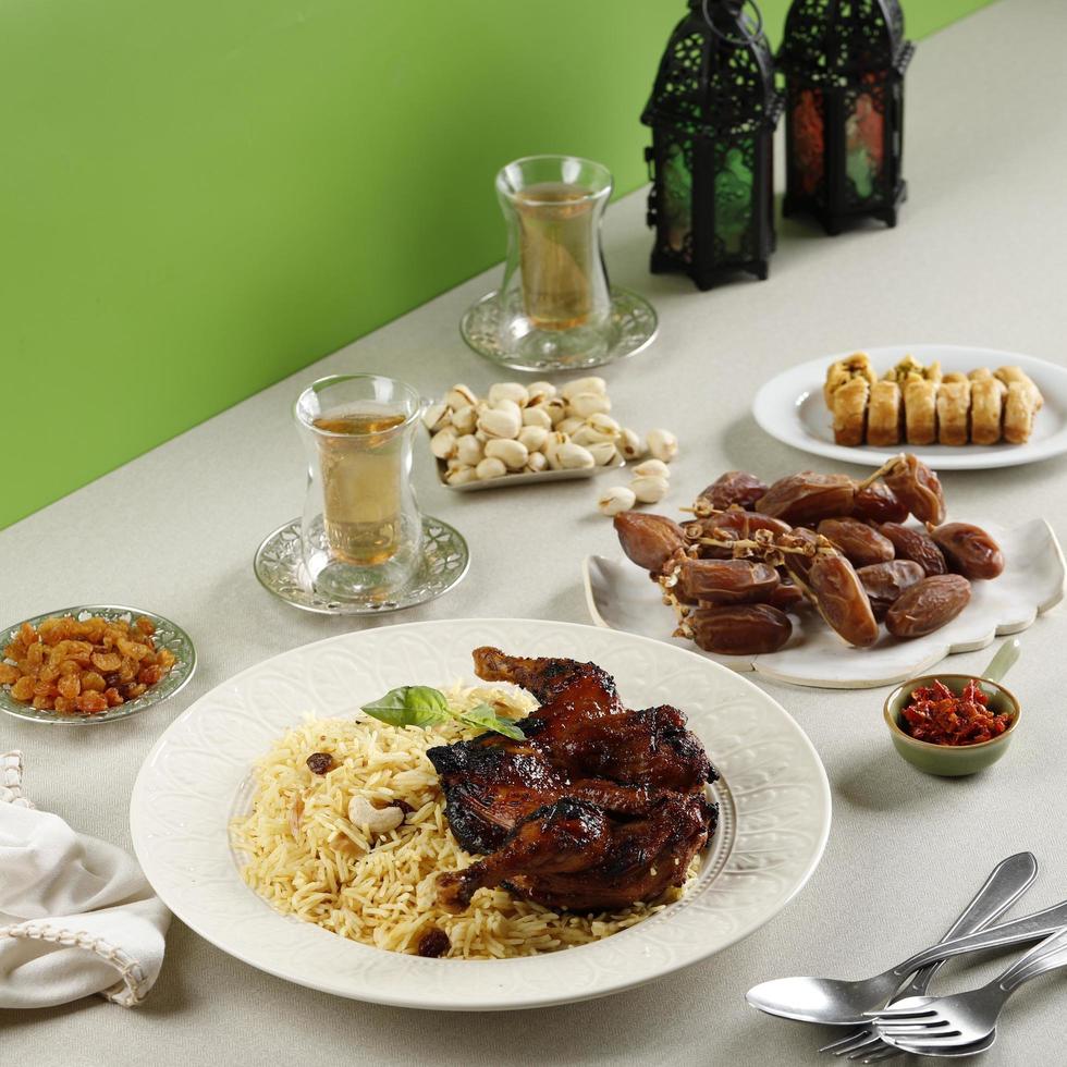 buffet de menu iftar do ramadã, kabsa de arroz basmati com frango assado, passas, chá, tâmaras, pistache e baklava turca foto