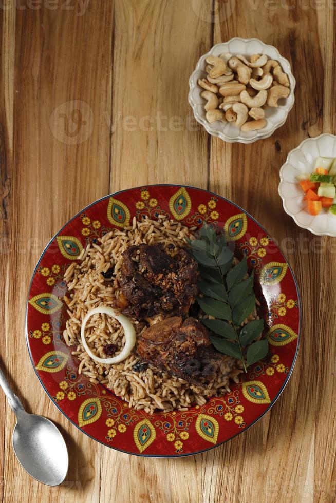 delicioso pilaf asiático com costelas de cordeiro temperadas em um prato marroquino vermelho. foto