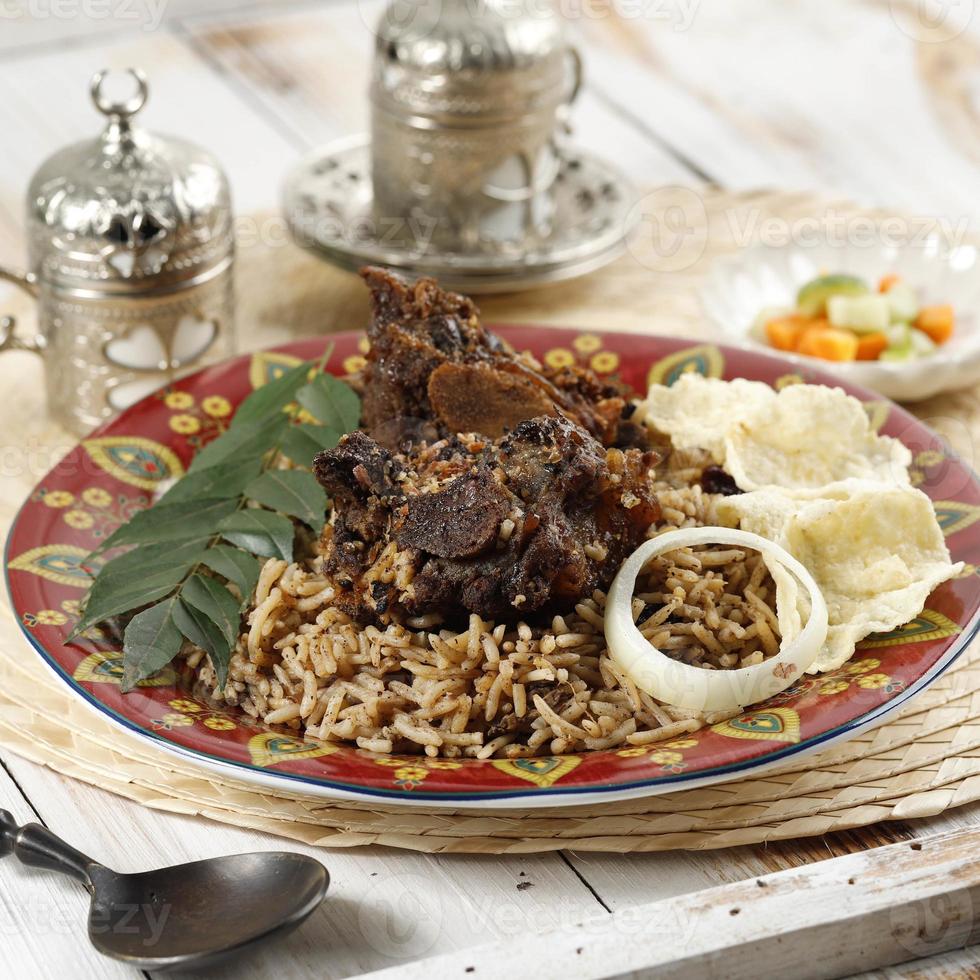 arroz nasi kebuli kabuli, pilaf árabe ou indiano com costelas de carne ou cordeiro, na mesa de madeira foto