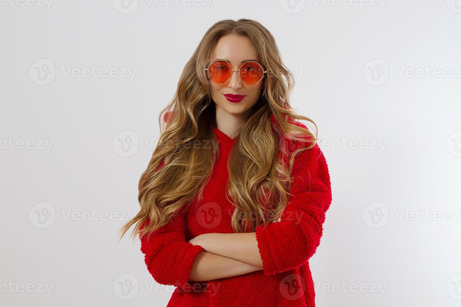 rosto de mulher closeup em óculos de sol vermelhos, isolados no fundo branco. garota de moletom com capuz vermelho e maquiagem de lábios vermelhos. conceito de beleza de moda. cabelo bonito e conceito de acessórios da moda. foto