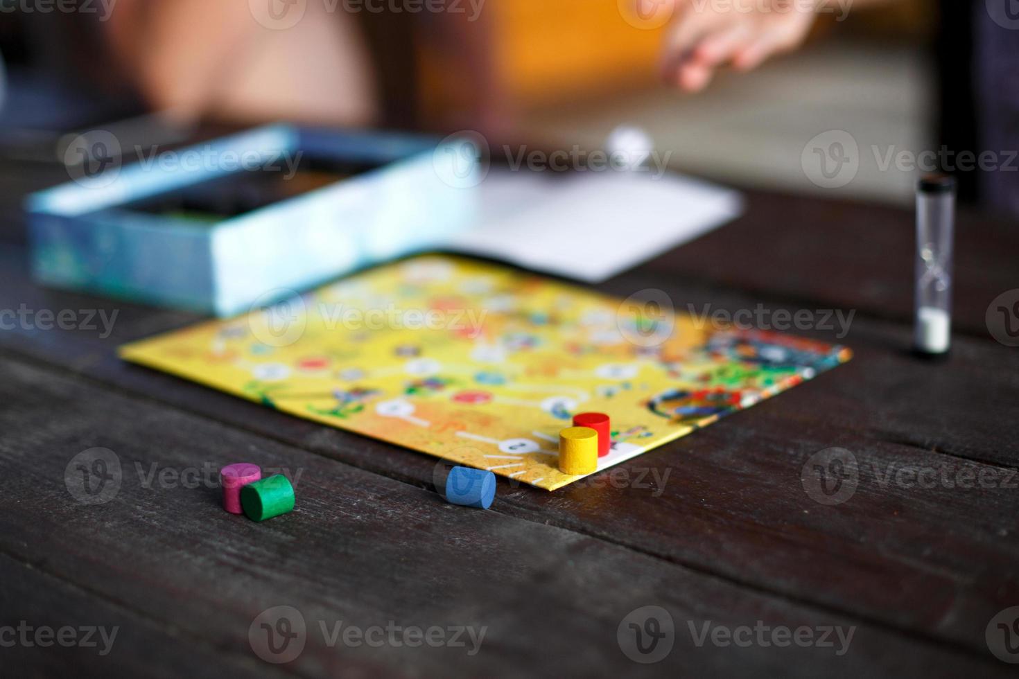 tabuleiro de jogo de tabuleiro, batatas fritas, cubo, temporizador em uma mesa de madeira escura e mãos ao fundo. o conceito de trabalho em equipe, relaxamento intelectual, evento corporativo, brincar em casa com as crianças. espaço de cópia foto