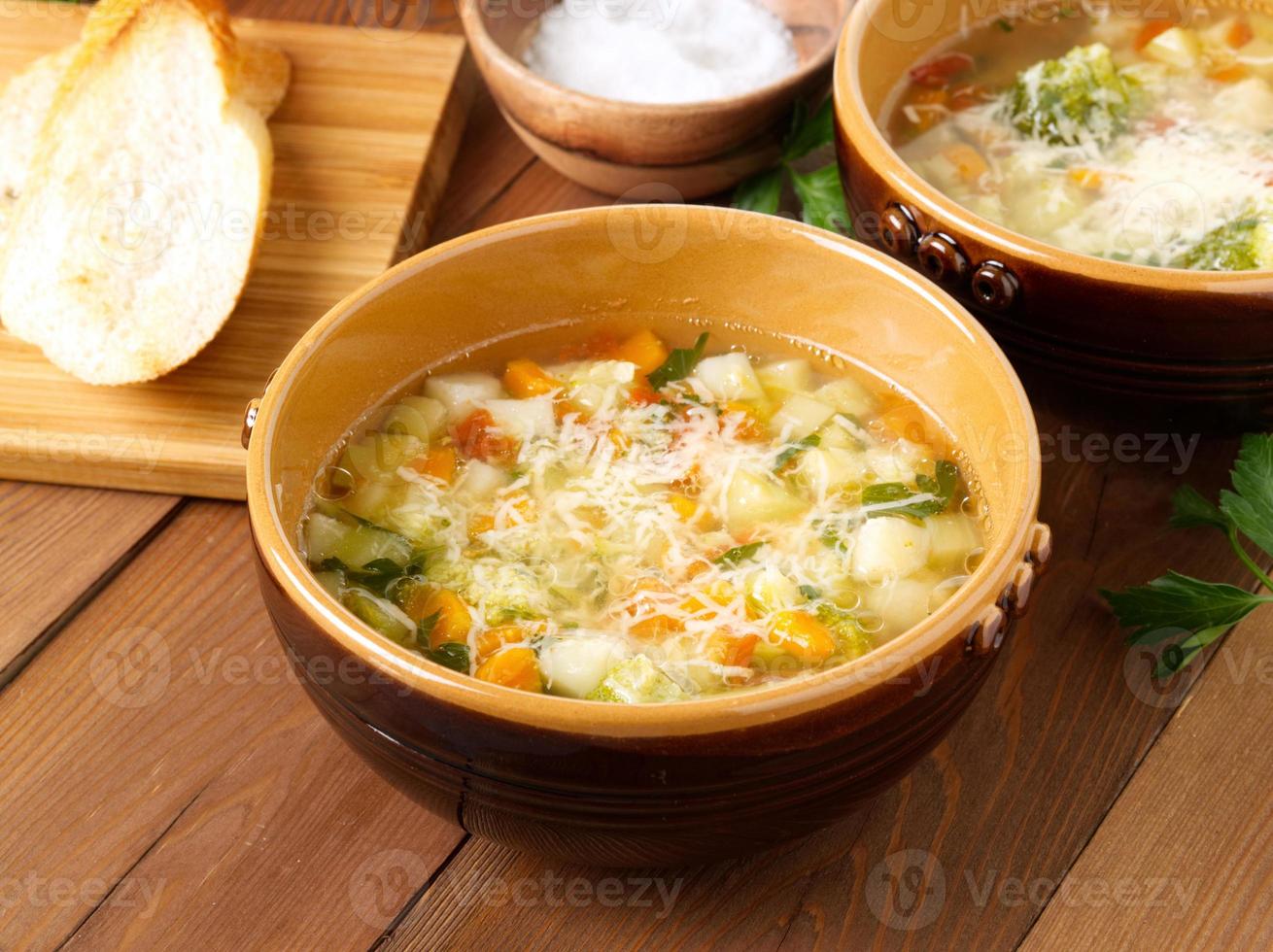 duas tigelas de sopa minestrone com torradas em fundo de madeira rústica, vista lateral. foto