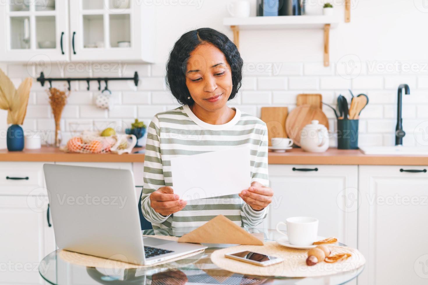 jovem mulher afro-americana abrindo e lendo a carta de papel. conceito de receber correspondência foto