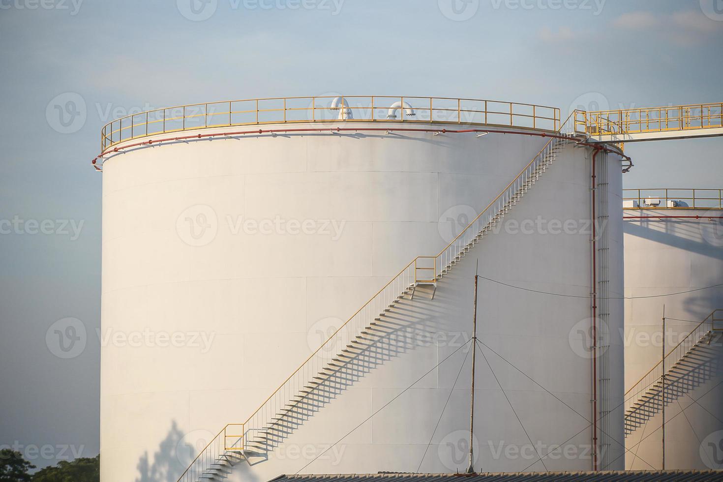 grandes tanques industriais para gasolina e óleo com tanques sky.fuel azul na fazenda de tanques. escadas de metal na lateral de um recipiente de óleo industrial. escada no grande tanque de combustível foto