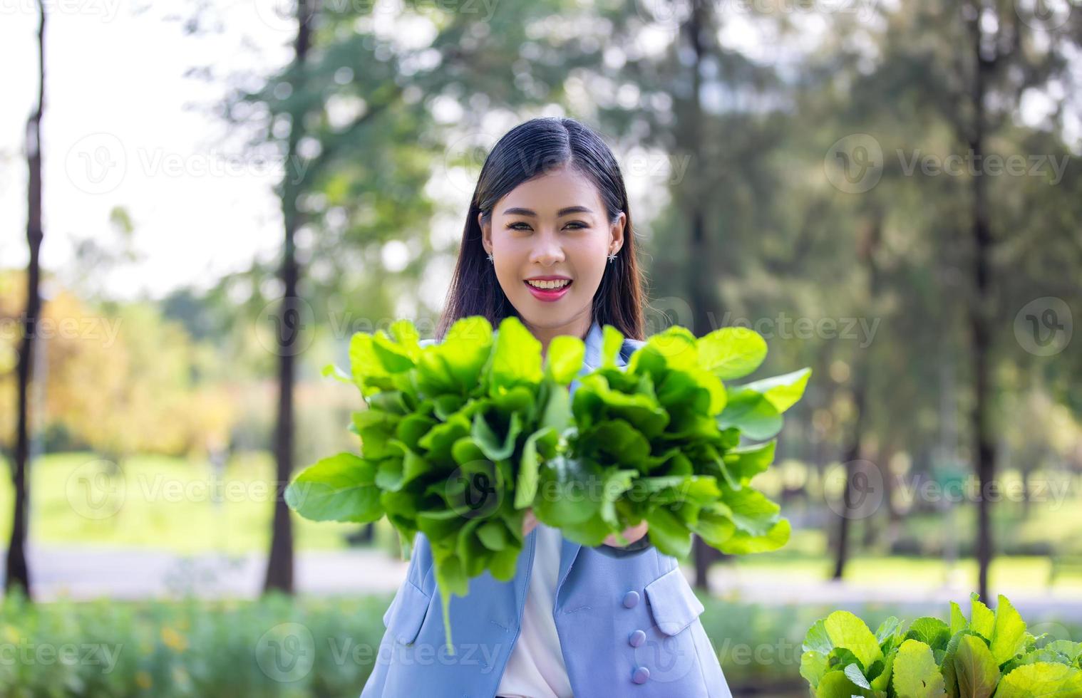 jovem mulher atraente colheita de vegetais na fazenda. jovem mulher asiática colher e pegar horta orgânica fresca na cesta na fazenda hidropônica, agricultura para o conceito de comida saudável foto