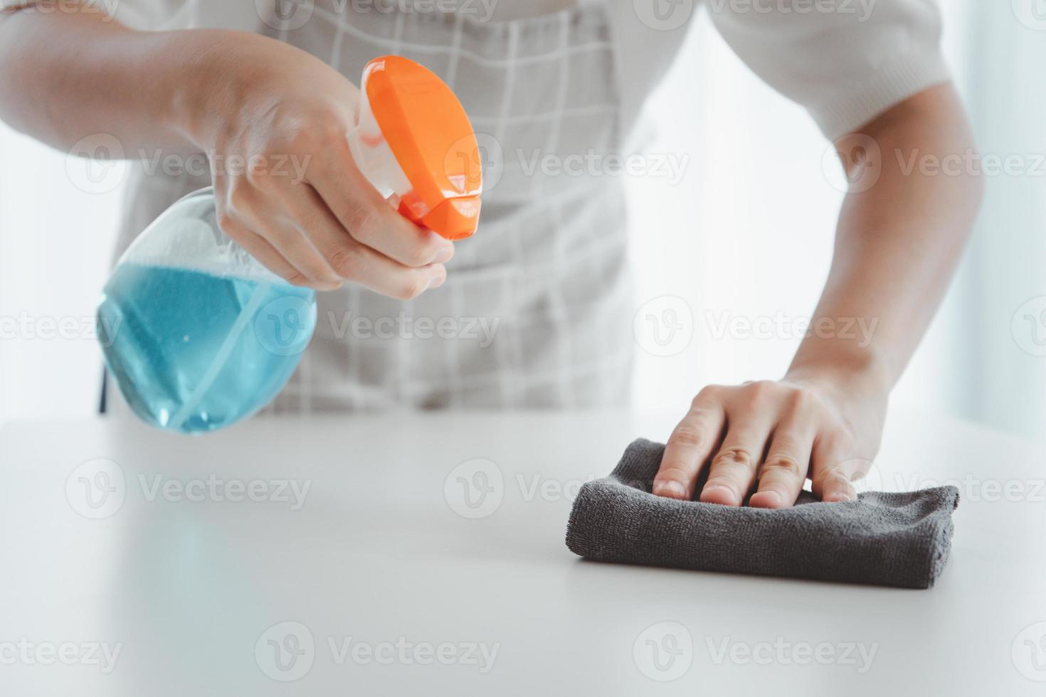dona de casa irreconhecível limpando a superfície da mesa usando desinfetante. foto