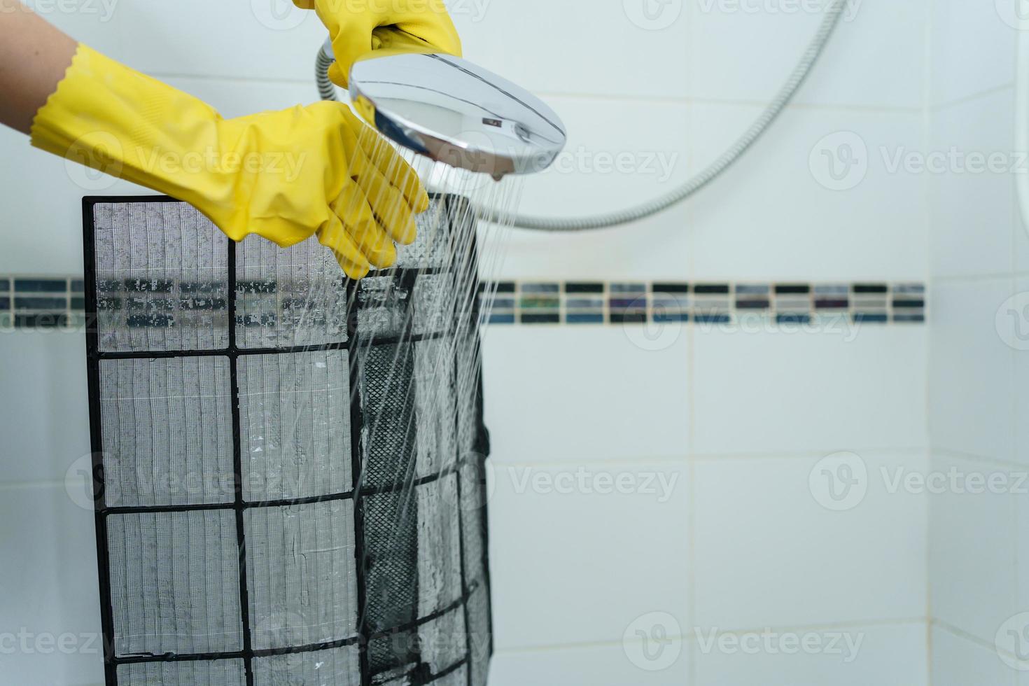 mulher asiática limpando um filtro de ar condicionado sujo e empoeirado em sua casa. dona de casa removendo um filtro de ar condicionado empoeirado. foto