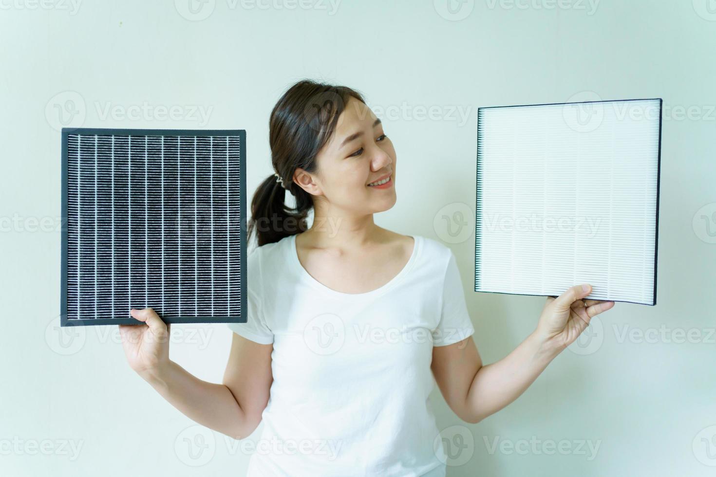 jovem asiática mostrando um filtro de purificador de ar usado e novo, comparando entre filtro de ar novo e sujo usado. foto