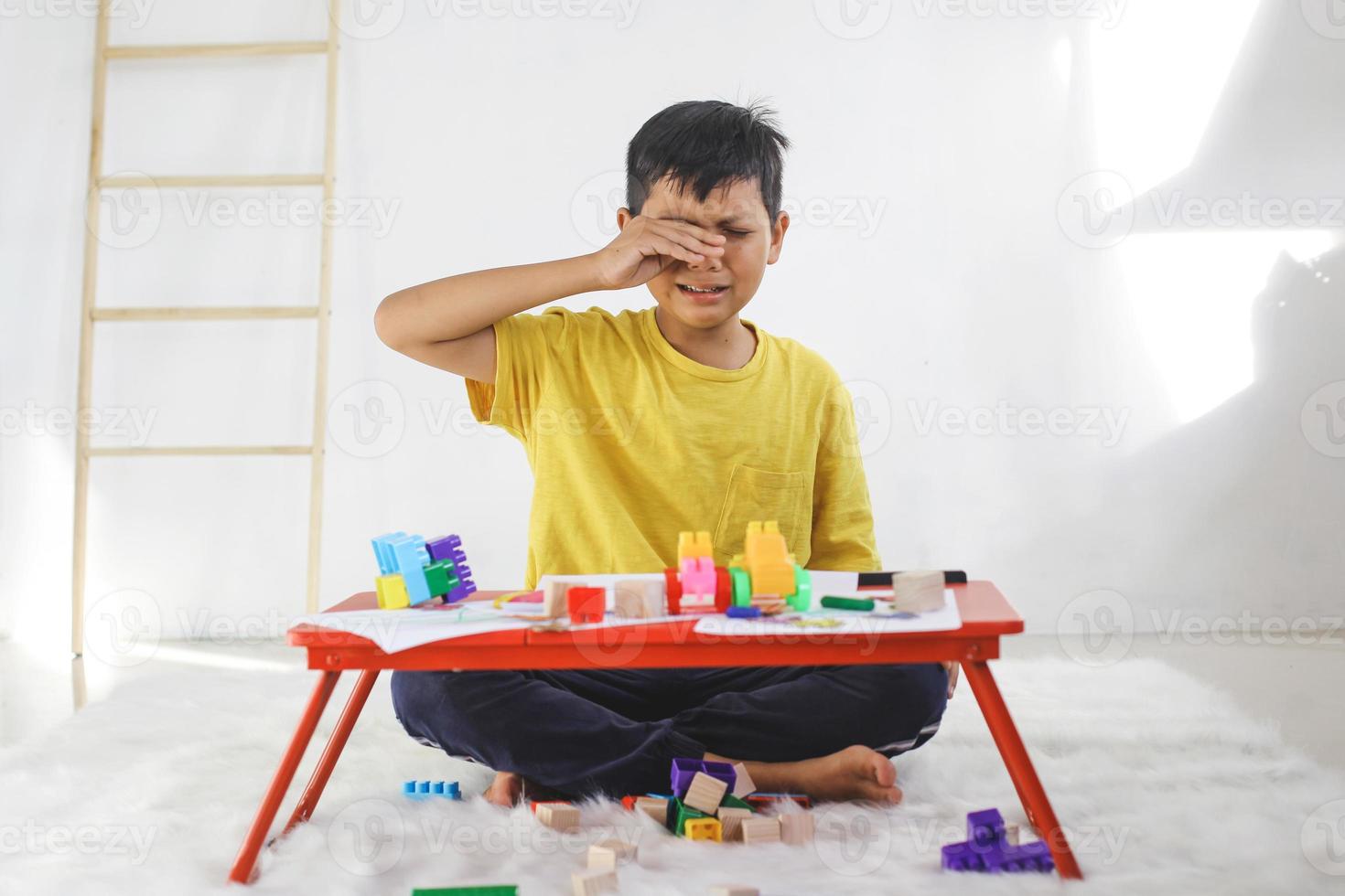 menino chorando enquanto brincava sozinho em casa. experiência traumática na infância, psicologia, psicológica, síndrome de asperger, transtorno de asperger, autista, autismo. foto