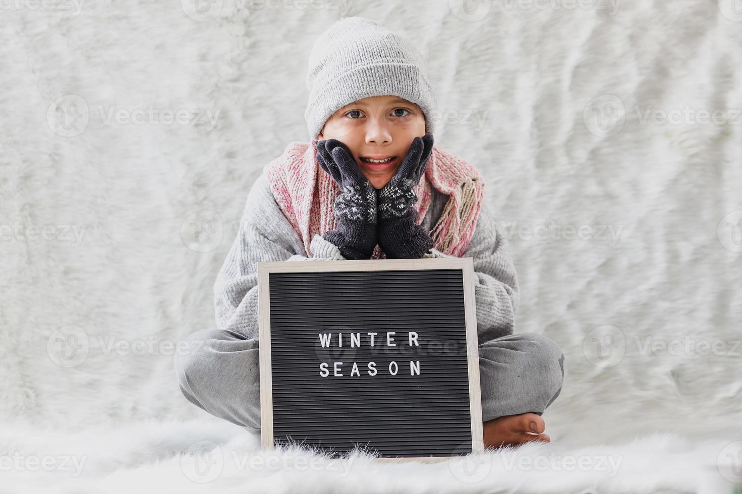 um menino vestindo roupas de inverno dá as boas-vindas à temporada de inverno alegremente foto