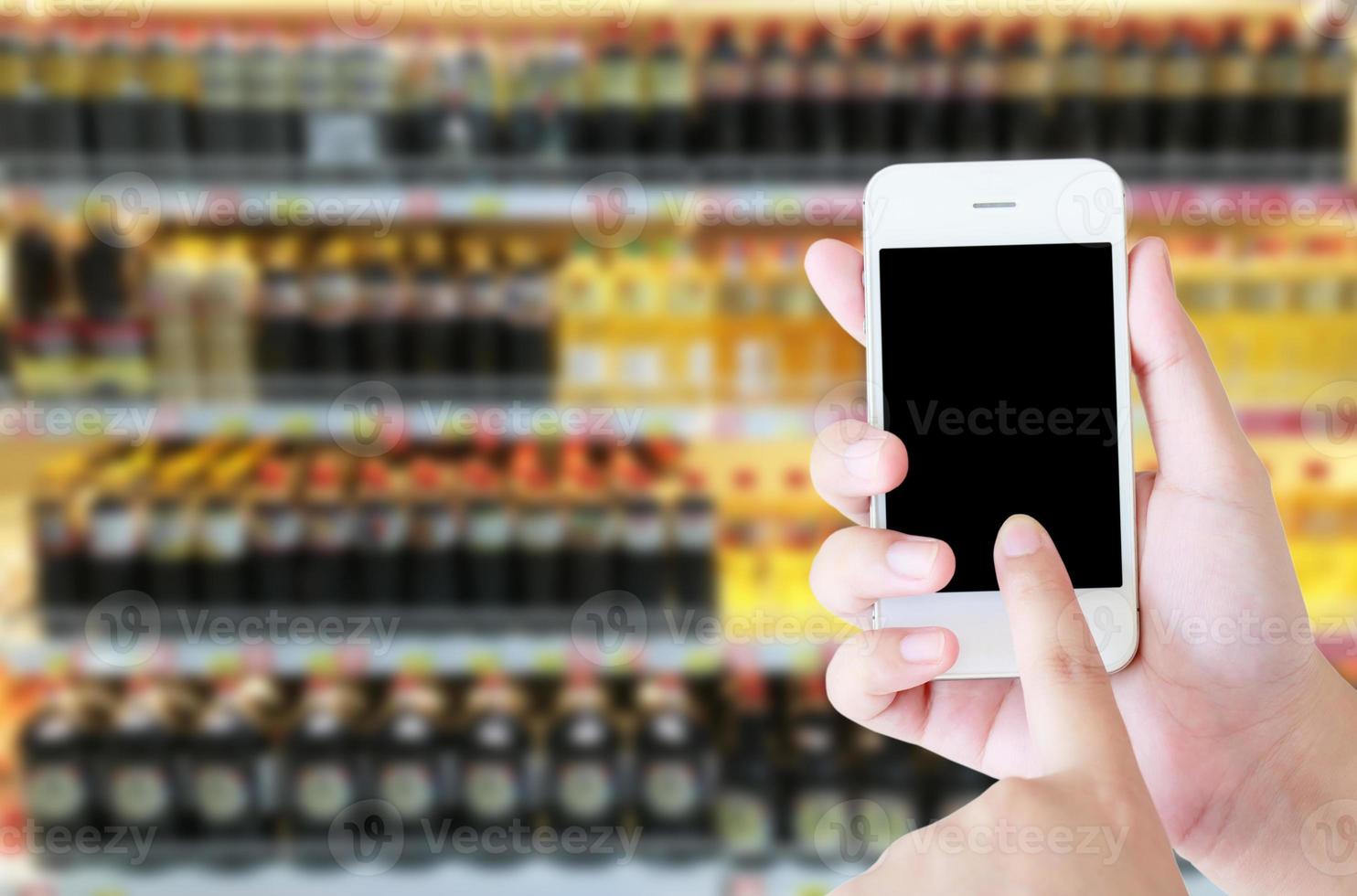 mão feminina segurando o telefone inteligente móvel no supermercado desfocar o fundo, conceito de negócio foto