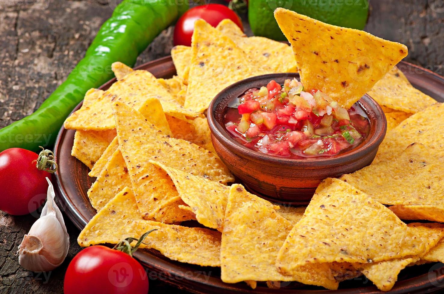 chips de nacho mexicano e molho de salsa na tigela sobre fundo de madeira foto