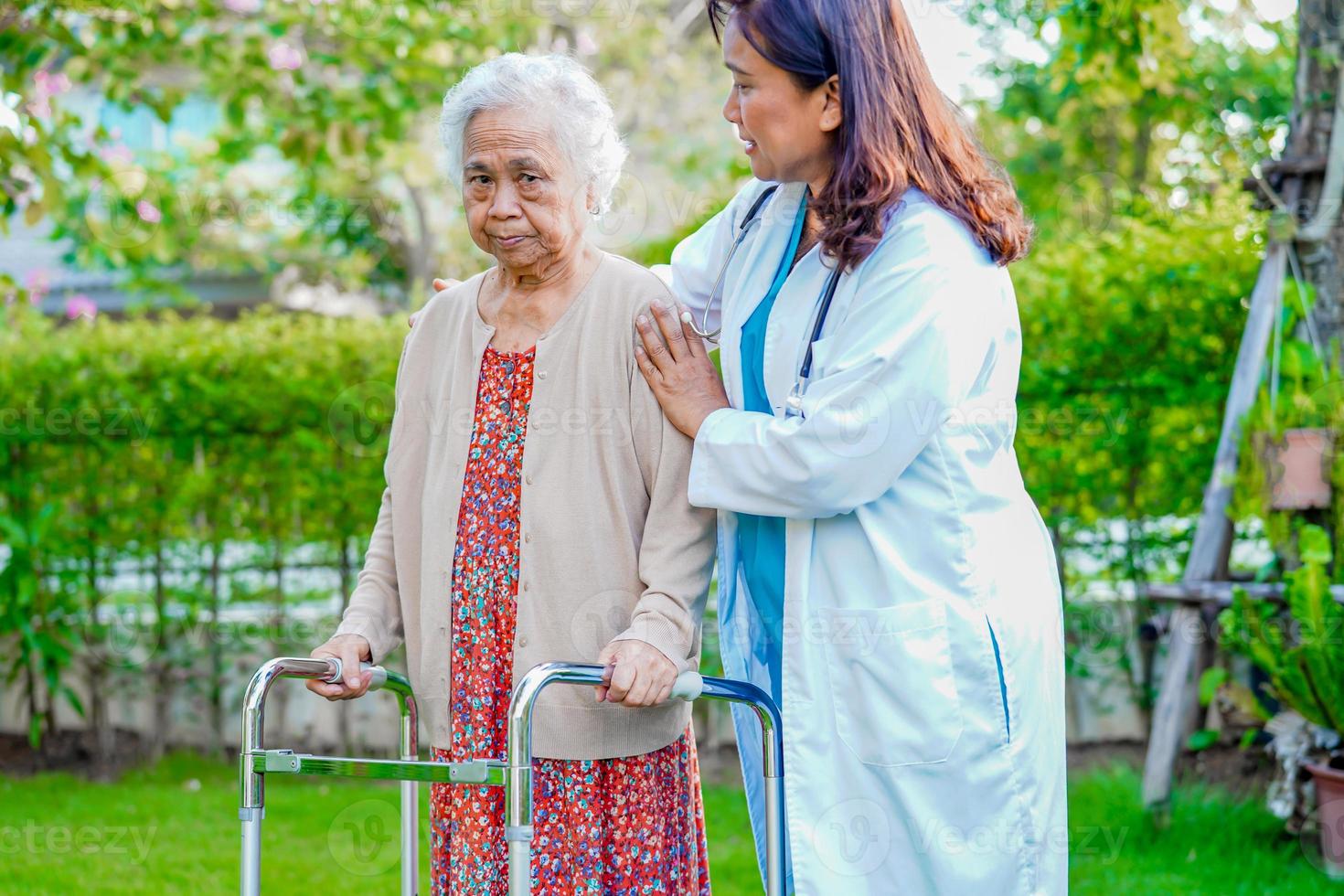 médico ajuda paciente idosa asiática com deficiência andar com caminhante no parque, conceito médico. foto