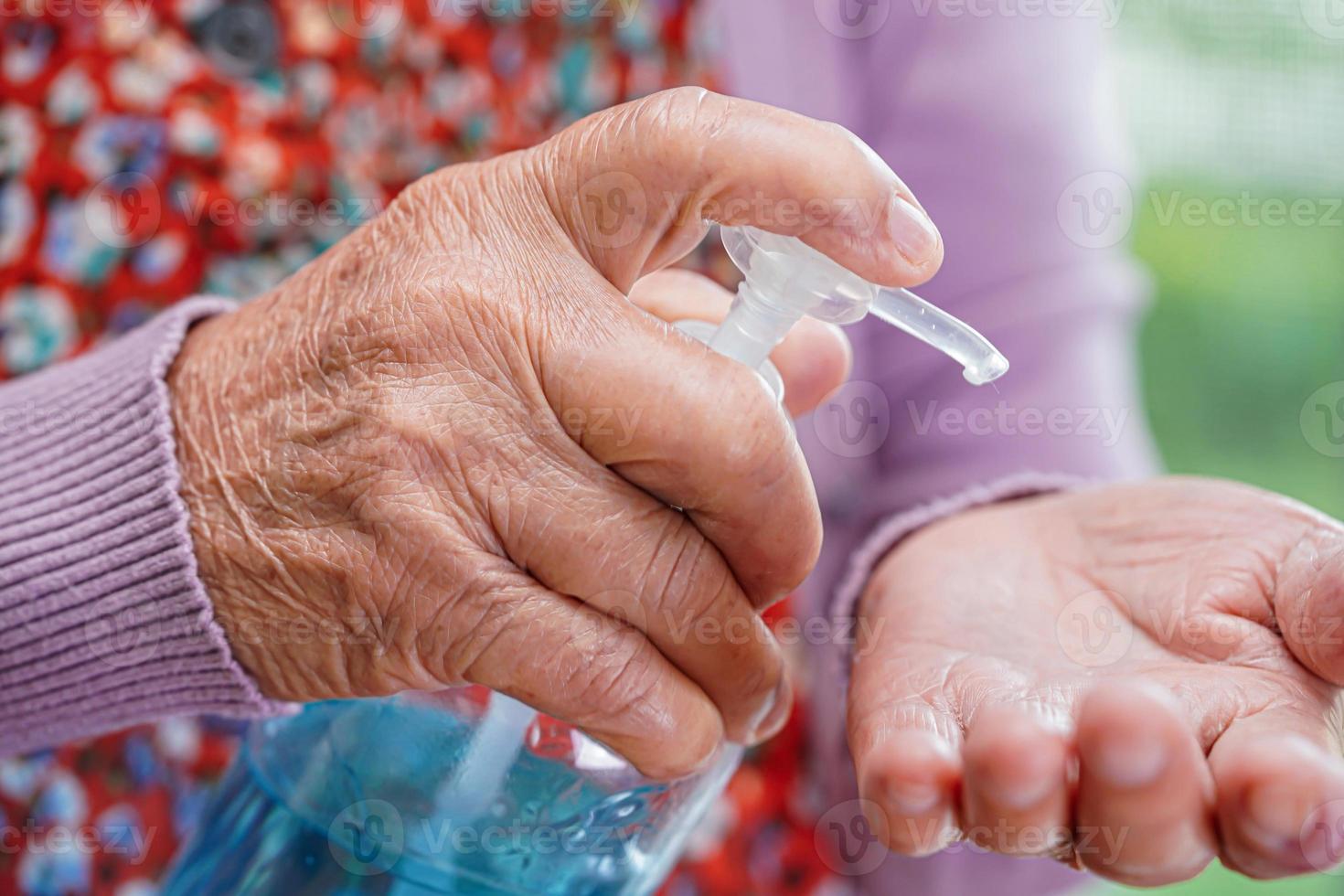 mulher idosa asiática pressione gel desinfetante de álcool azul para lavar as mãos proteger a infecção coronavírus. foto