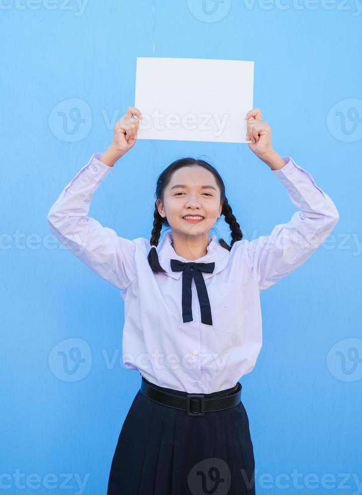 menina da escola segurando outdoor sobre fundo azul. foto