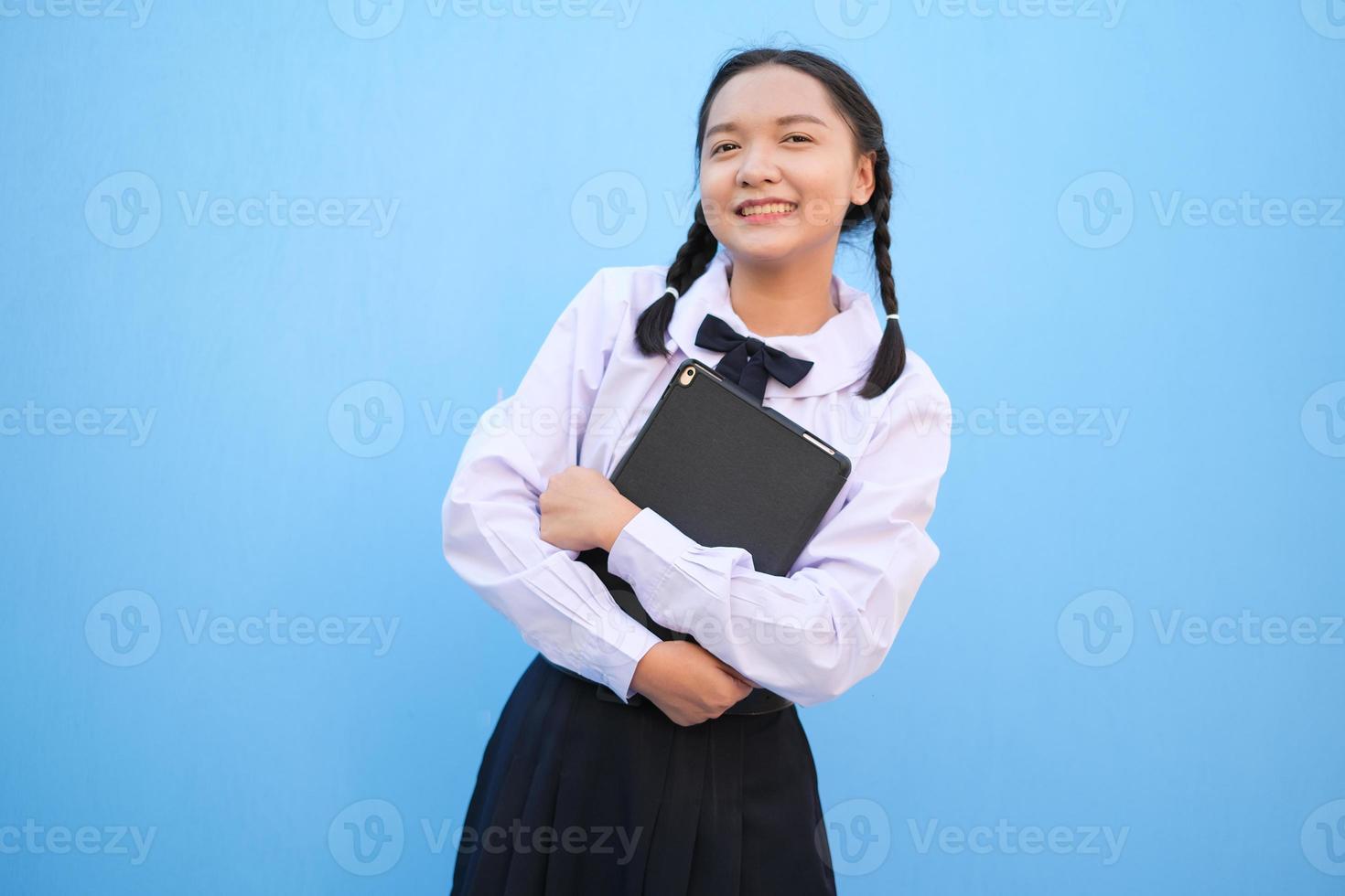 menina da escola segurando o tablet sobre fundo azul. foto