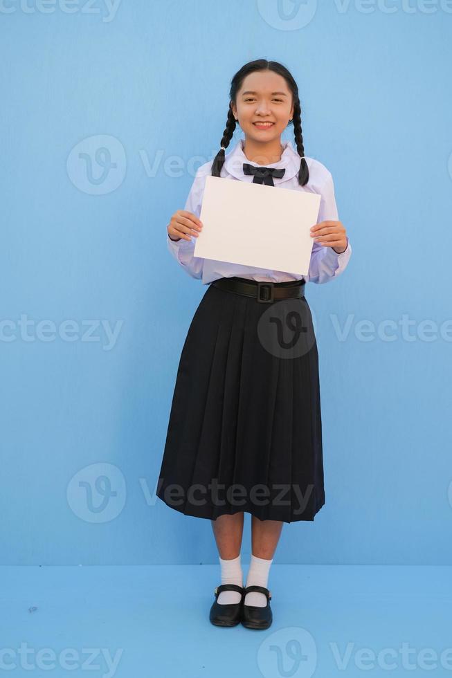 menina da escola segurando outdoor sobre fundo azul. foto