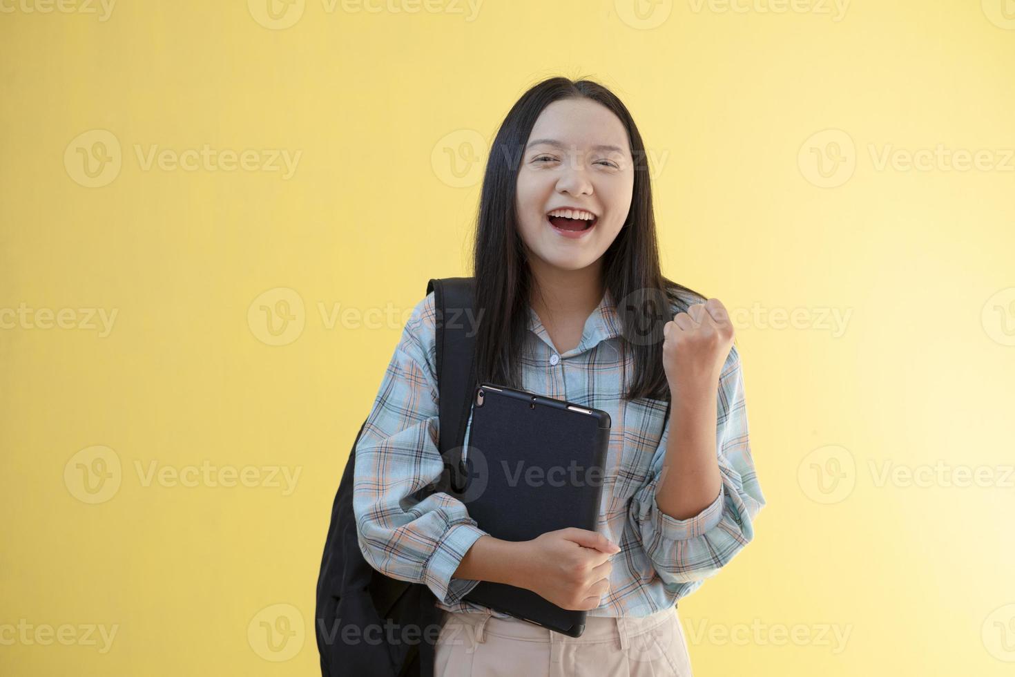 linda jovem com mochila e segure o laptop em fundo amarelo. foto