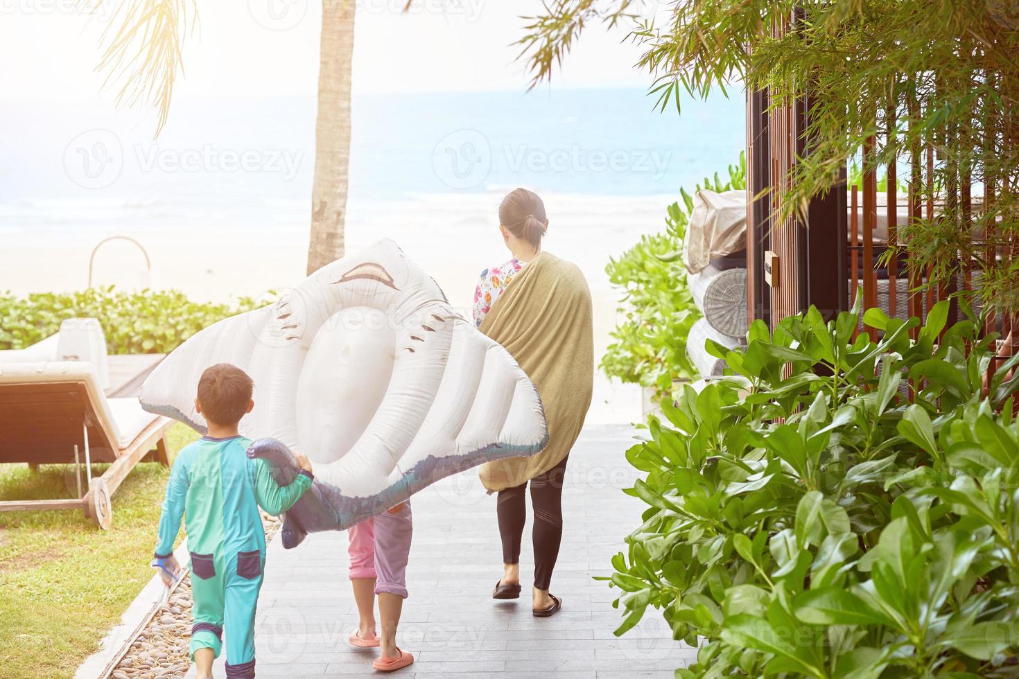 viagem em família a pé até a praia com flutuador de brinquedo no conceito de férias foto