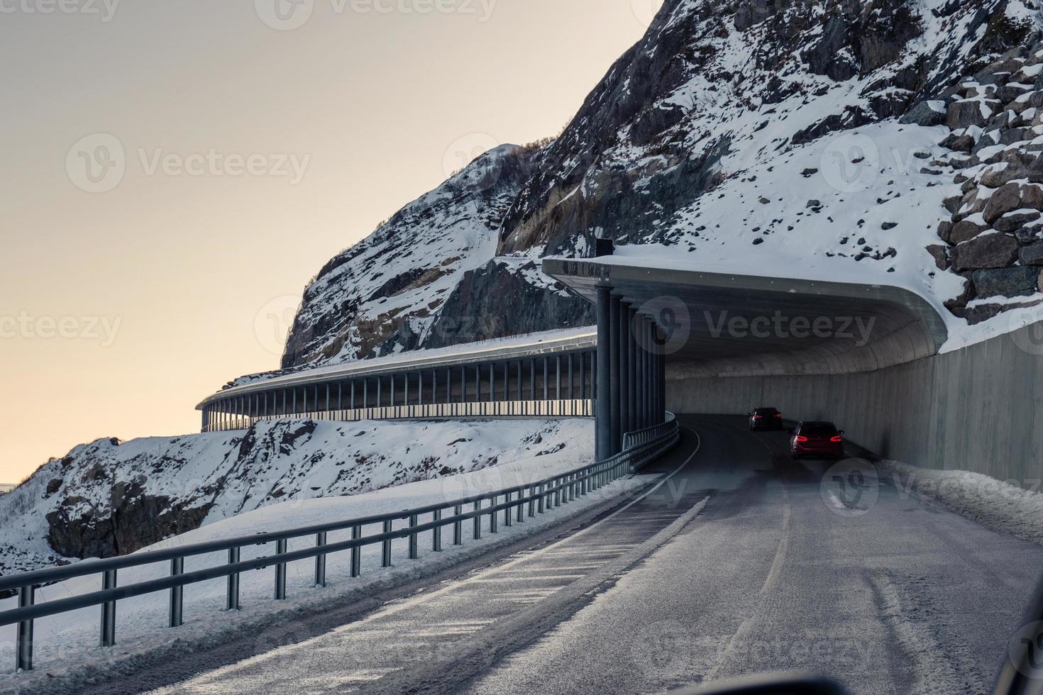 estrada de túnel com carro dirigindo pela montanha de neve no inverno nas ilhas lofoten foto