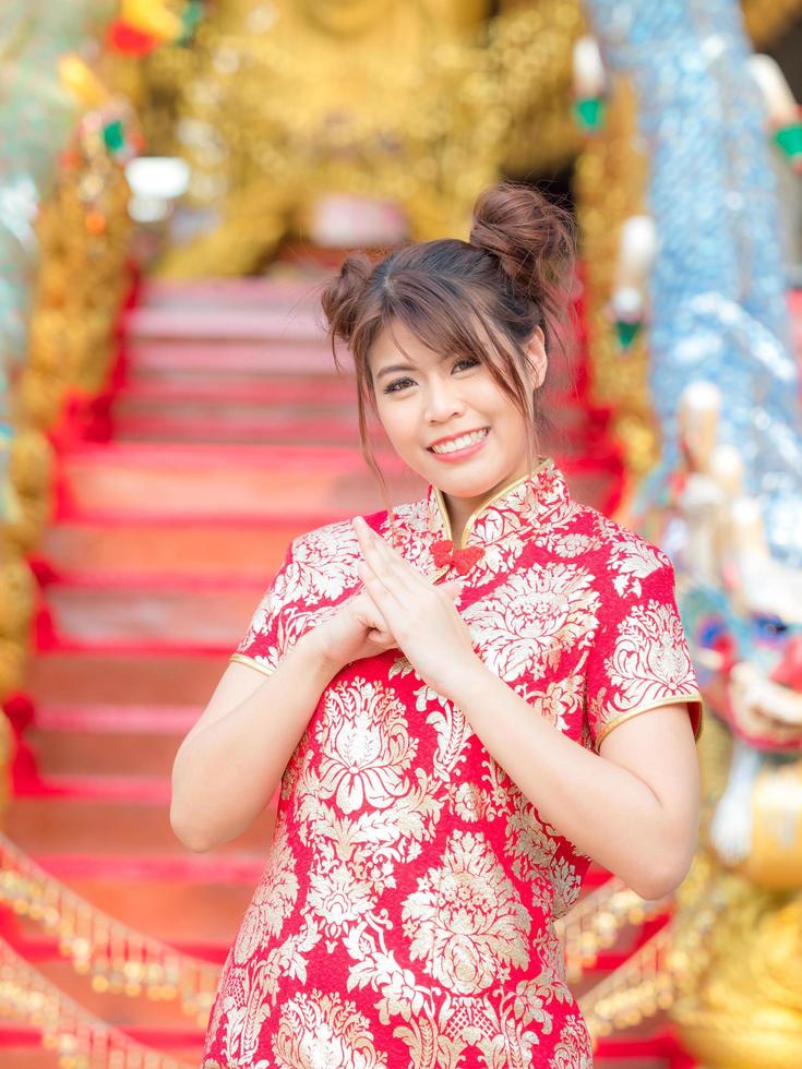 uma linda garota asiática em um traje nacional chinês levanta as mãos para se curvar foto