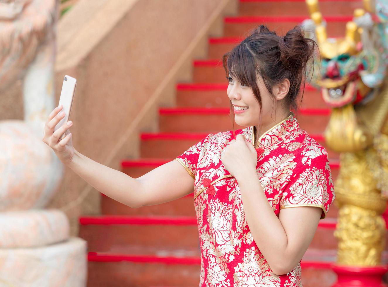 menina bonita asiática vestida com traje nacional chinês está tirando fotos