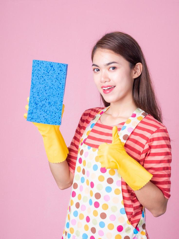 mulher bonita asiática segurando uma esponja para limpar o dispositivo e sorrindo alegremente para limpar a casa foto