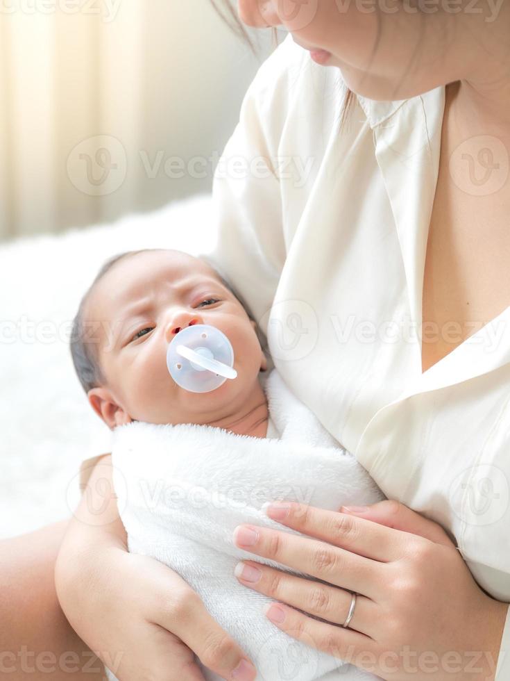 uma linda mulher asiática coloca seu bebê recém-nascido em seu corpo feliz e com amor foto