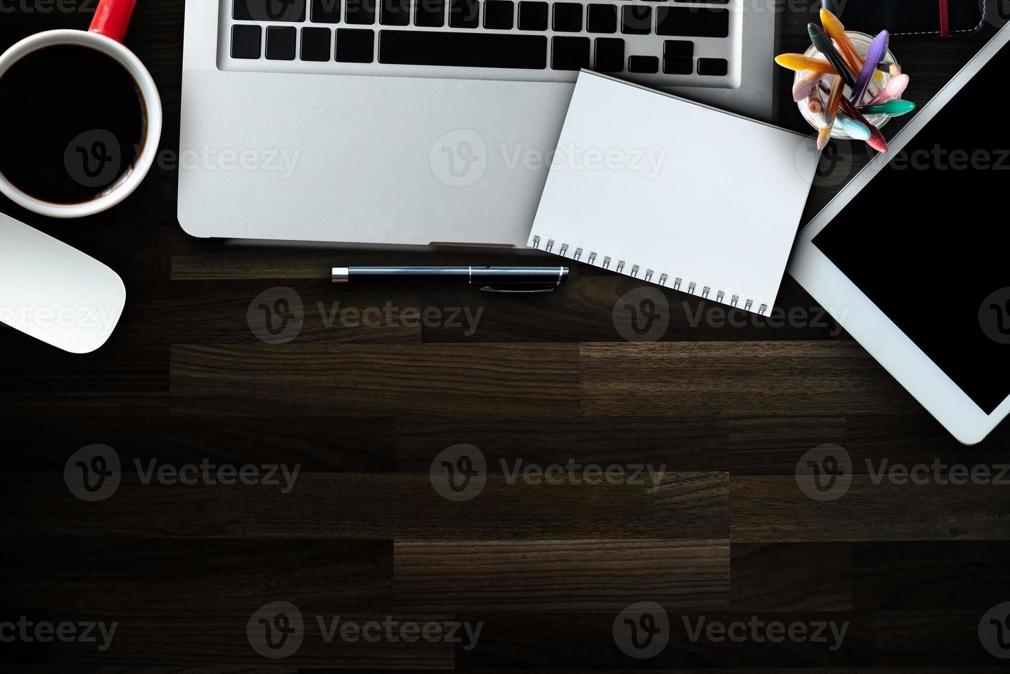 mesa de escritório de madeira com muitas coisas tablet, laptop, smartphone, bloco de notas e bloco de notas de xícara de café. vista superior com tela de ícones de interface virtual de espaço de cópia. foto