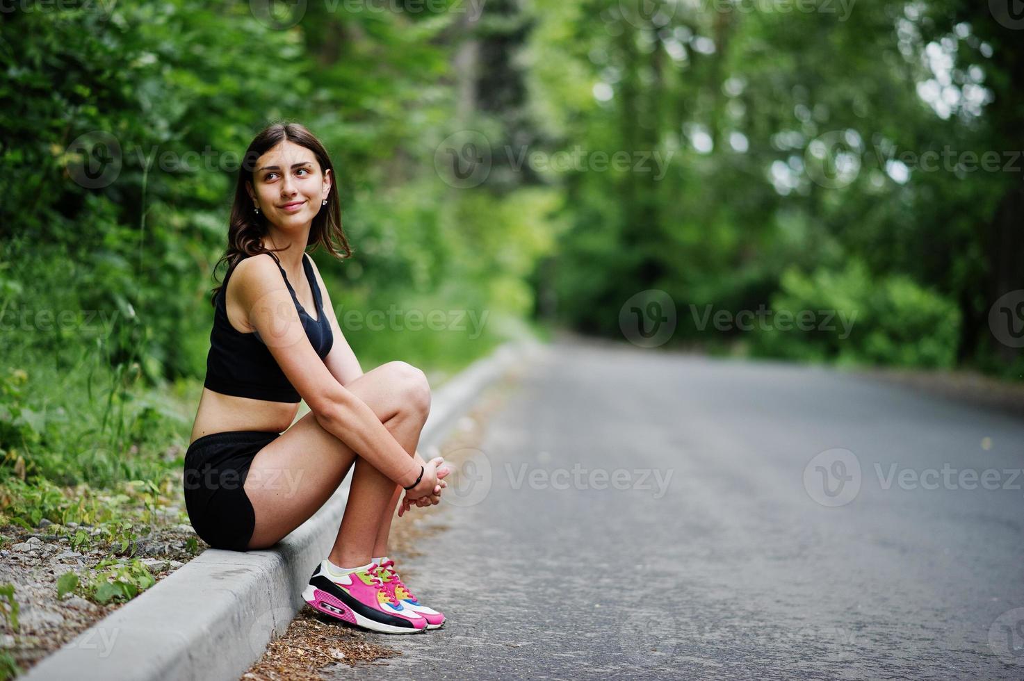 garota esportiva no sportswear descansando em um parque verde após o treino na natureza. um estilo de vida saudável. foto