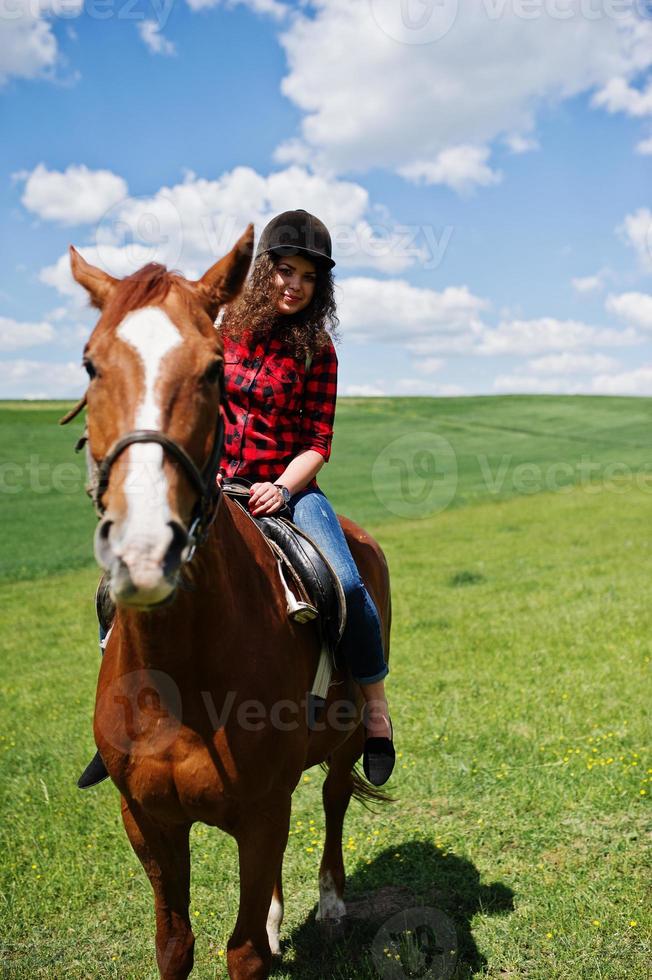 menina bonita andando a cavalo em um campo em dia ensolarado. foto