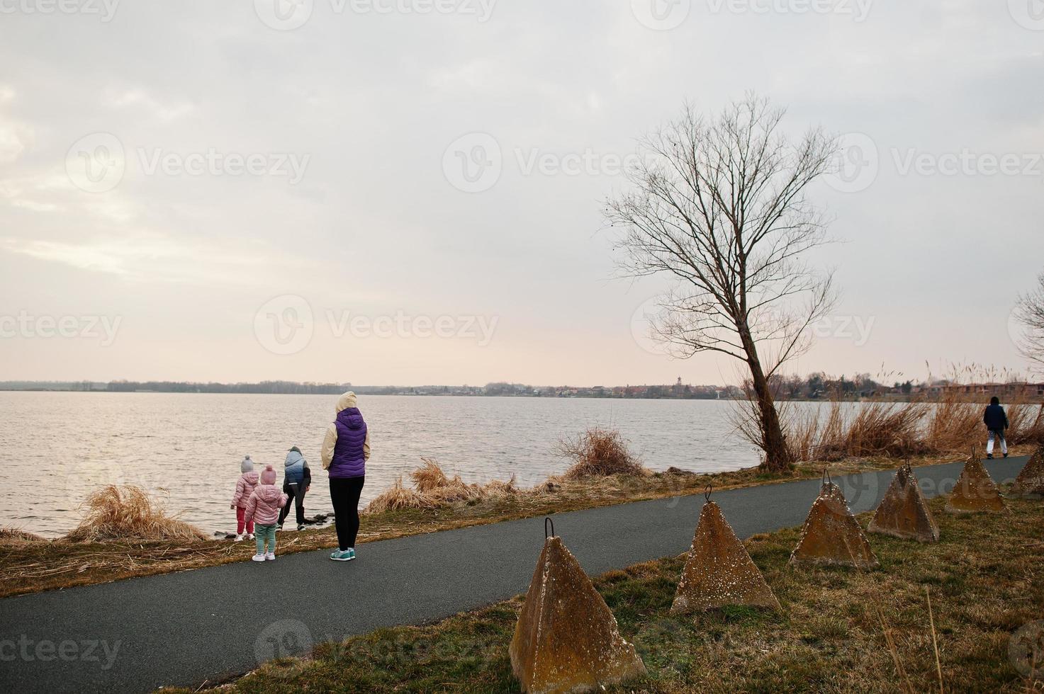 mãe com filhos na margem do lago. foto