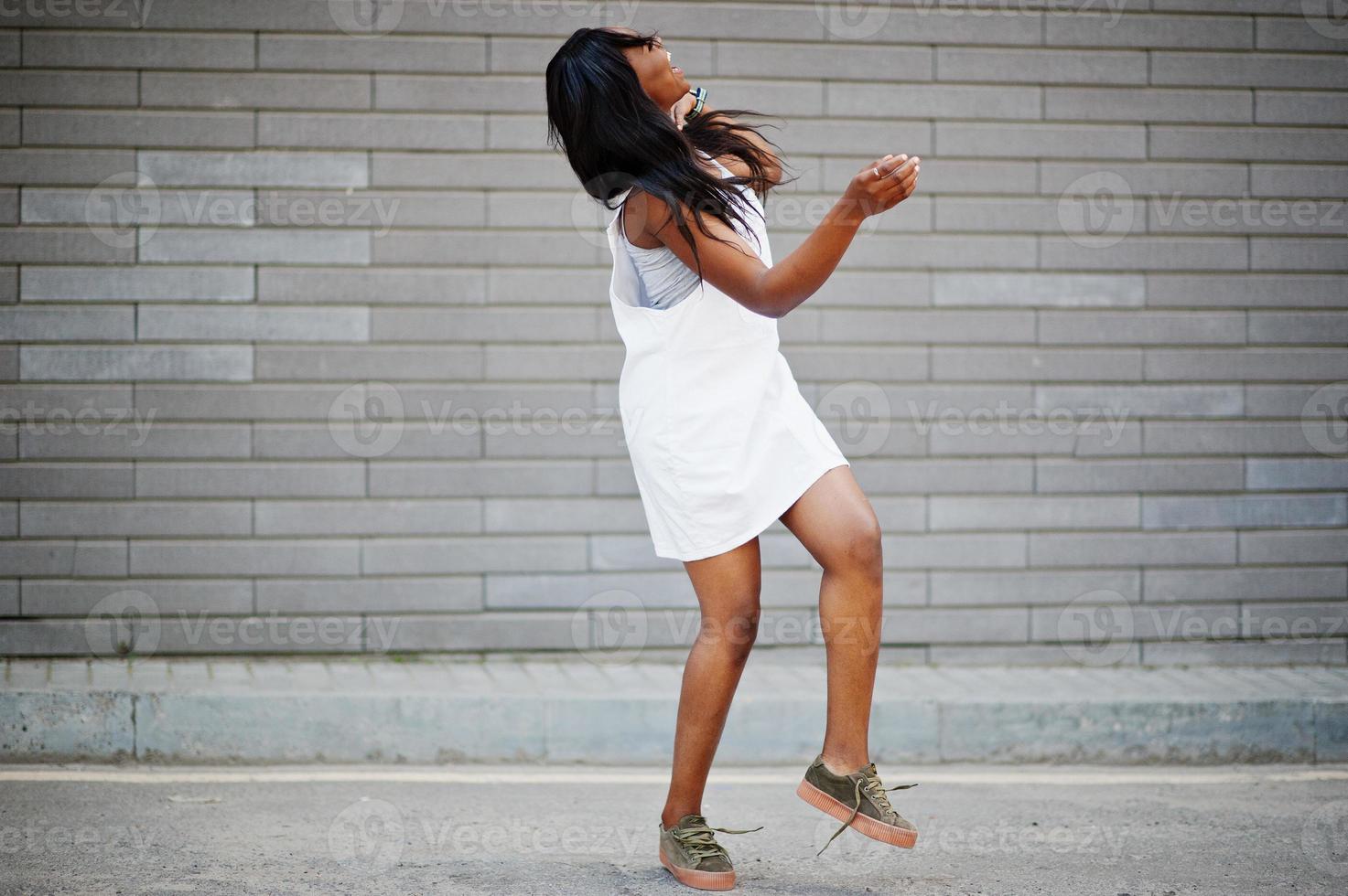 retrato de uma mulher afro-americana fabulosa dançando e pulando contra a parede de tijolos no fundo. foto