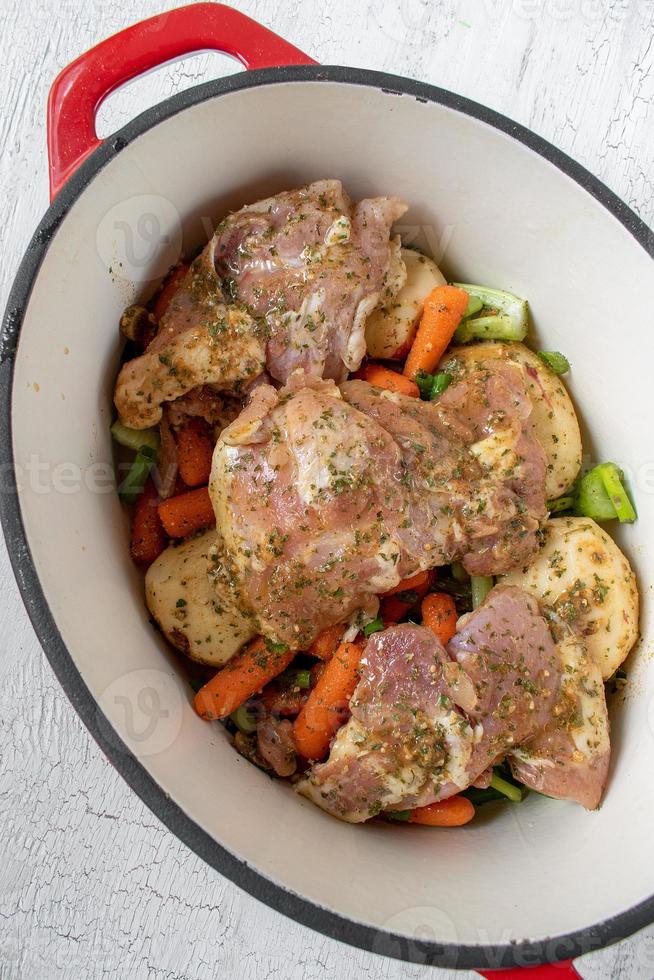 ensopado de frango coberto com legumes de batatas, cenouras e cebolas com ervas foto