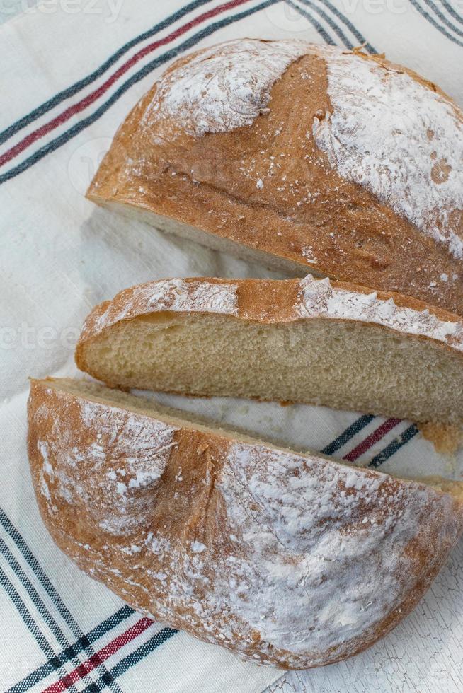pão redondo fatiado com topo enfarinhado na toalha de mesa de fazenda foto