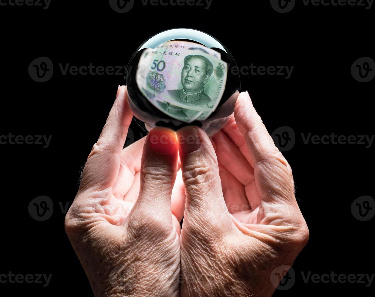 mãos segurando uma bola de previsão de vidro de cristal refletindo a cabeça na nota chinesa de 50 yuan foto