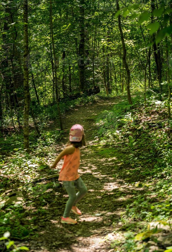 menina em uma floresta olhando para trás ao longo da trilha com atitude de medo foto