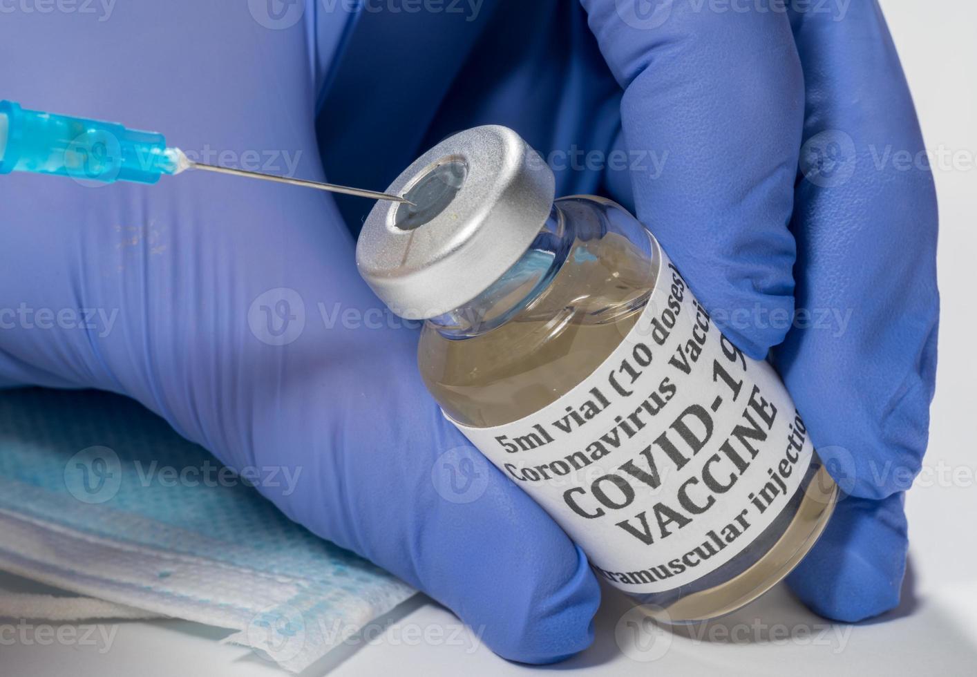 close-up da extremidade da seringa hipodérmica sendo inserida no frasco de vacina foto