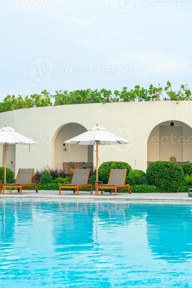 guarda-sol com cama piscina ao redor da piscina com fundo do mar oceano foto