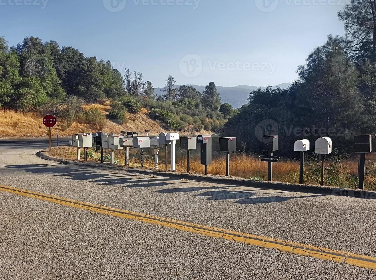 estrada americana com inúmeras caixas de correio colocadas uma após a outra e com a sombra refletida no asfalto da estrada da cidade foto