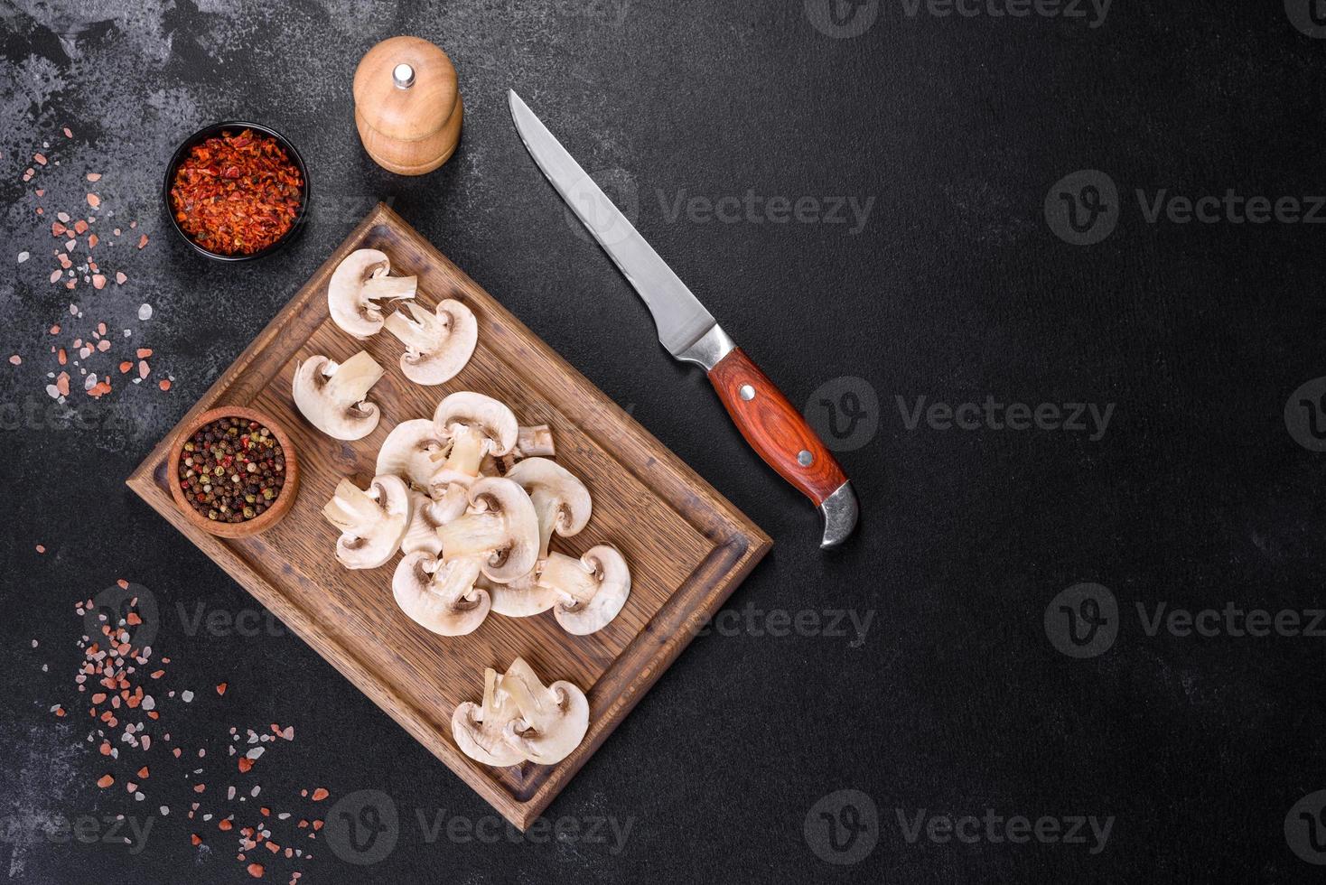 lindos jovens champignons brancos rasgados em fatias em um fundo escuro de concreto foto