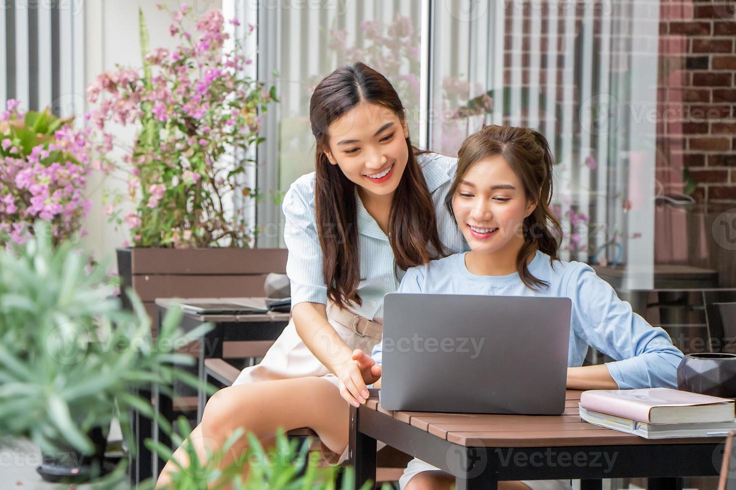 menina asiática olhando no laptop enquanto trabalhava com amiga juntos ao ar livre foto