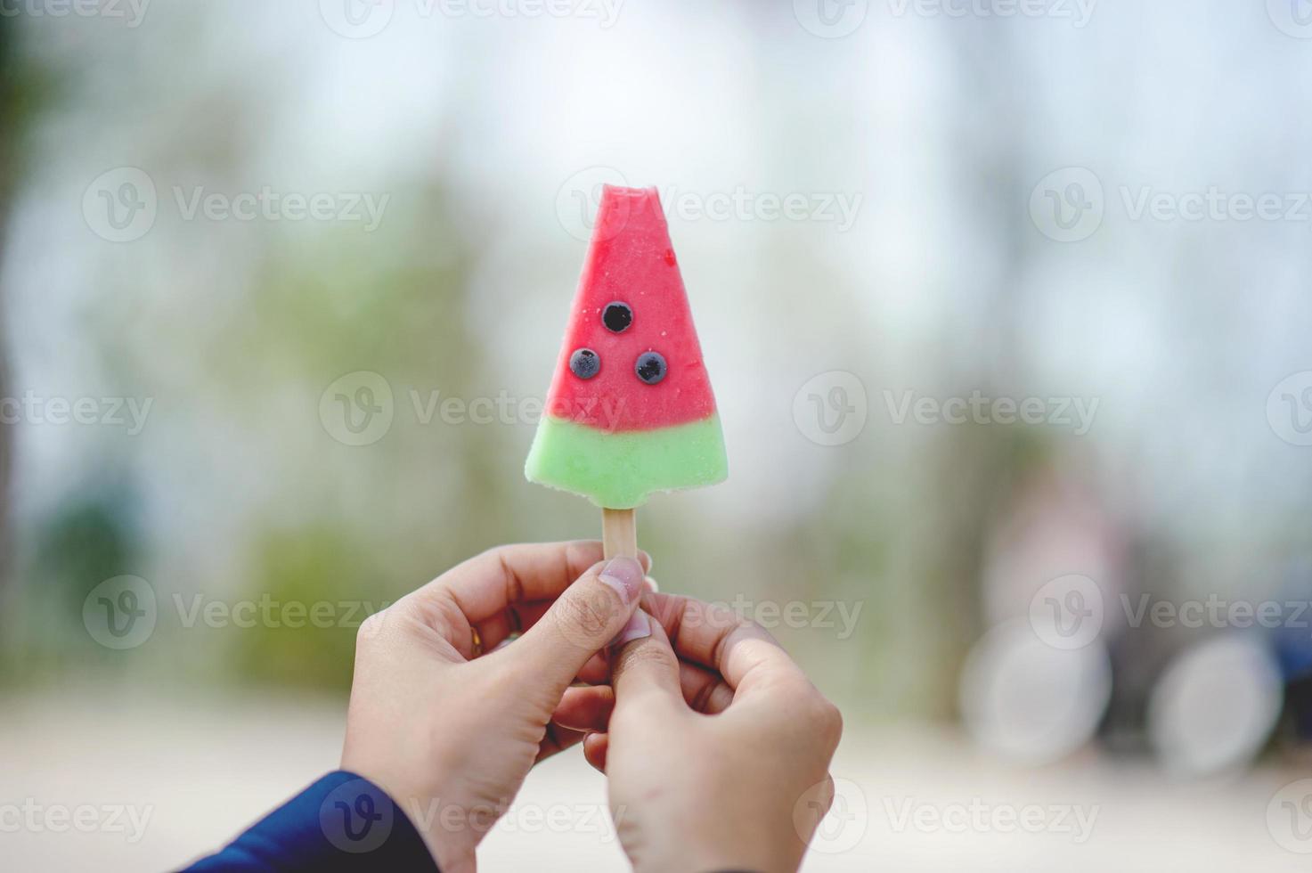 mão e sorvete vermelho comendo o conceito de sorvete com espaço de cópia foto