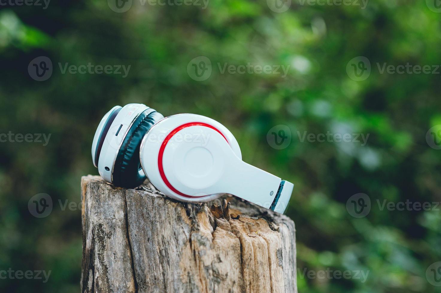 fones de ouvido brancos estão suspensos na madeira. área verde e relaxe. é ouvir música foto