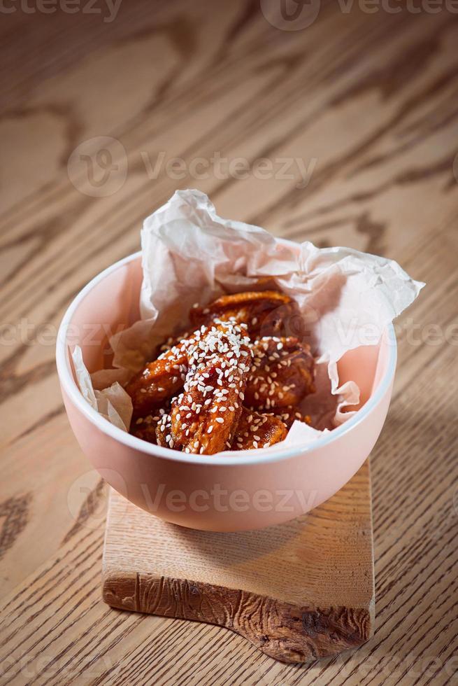 asas de frango frito com gergelim no prato na mesa foto