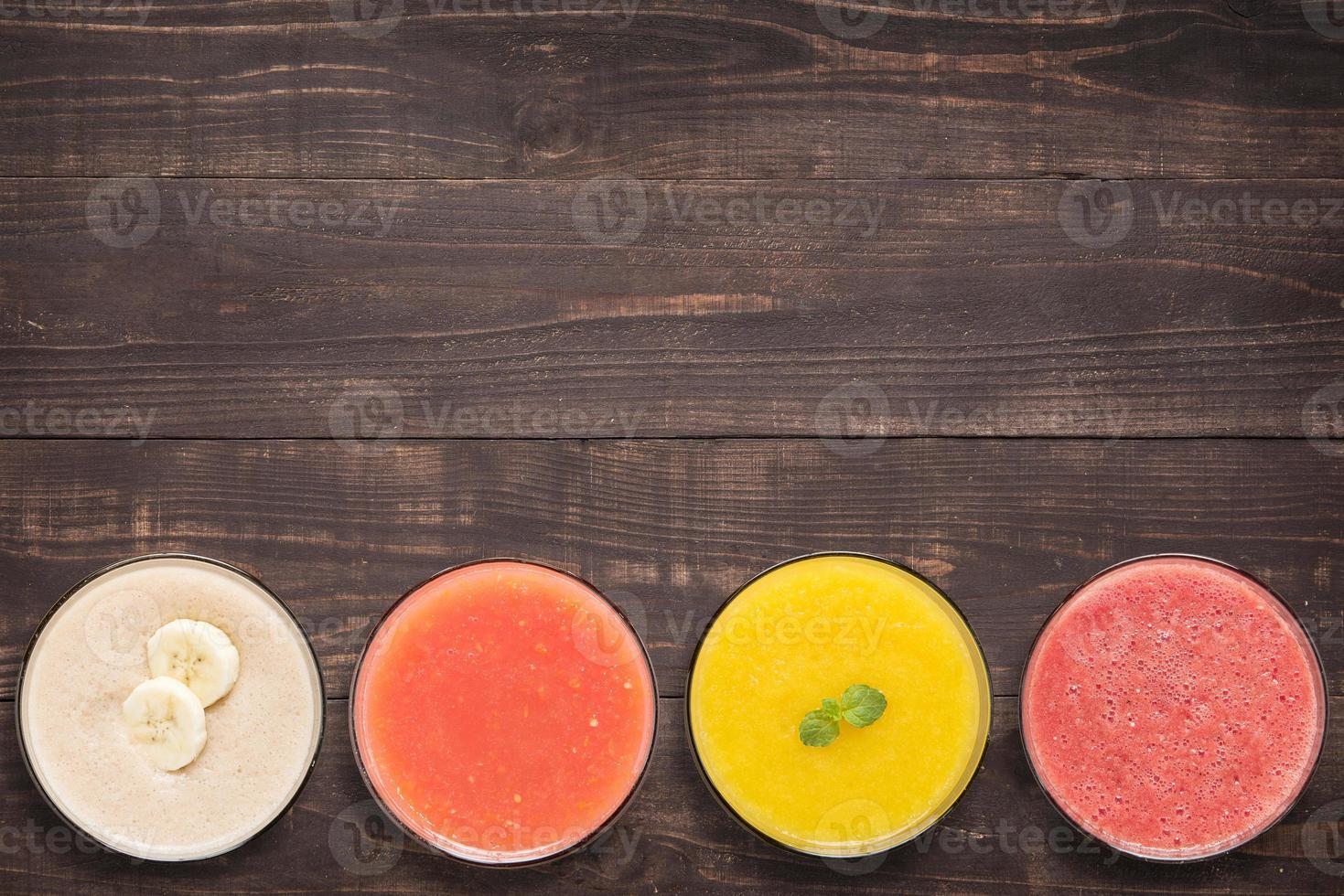 conjunto de smoothie da fruta e suco em copos na madeira foto