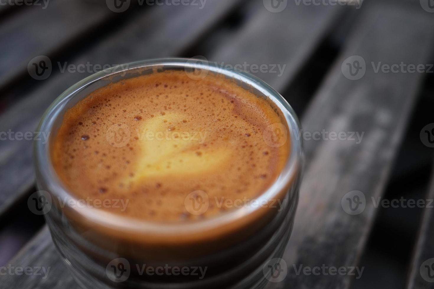 feche a foto de um copo de café com uma mistura de café expresso e suco de laranja, mostrando espuma brilhante com fundo desfocado.