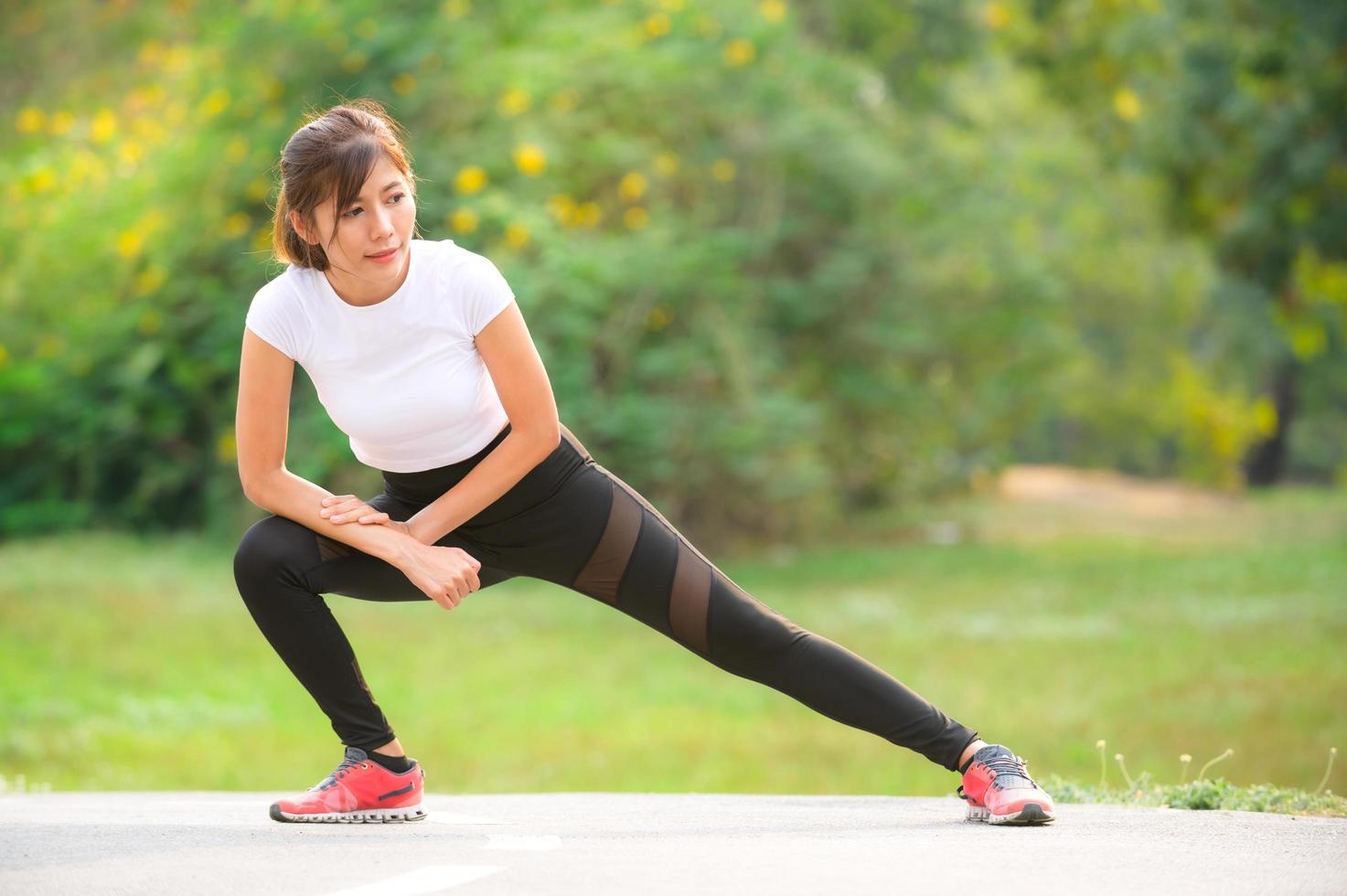 uma linda mulher asiática está se aquecendo, para tornar os músculos flexíveis antes de ir correr foto