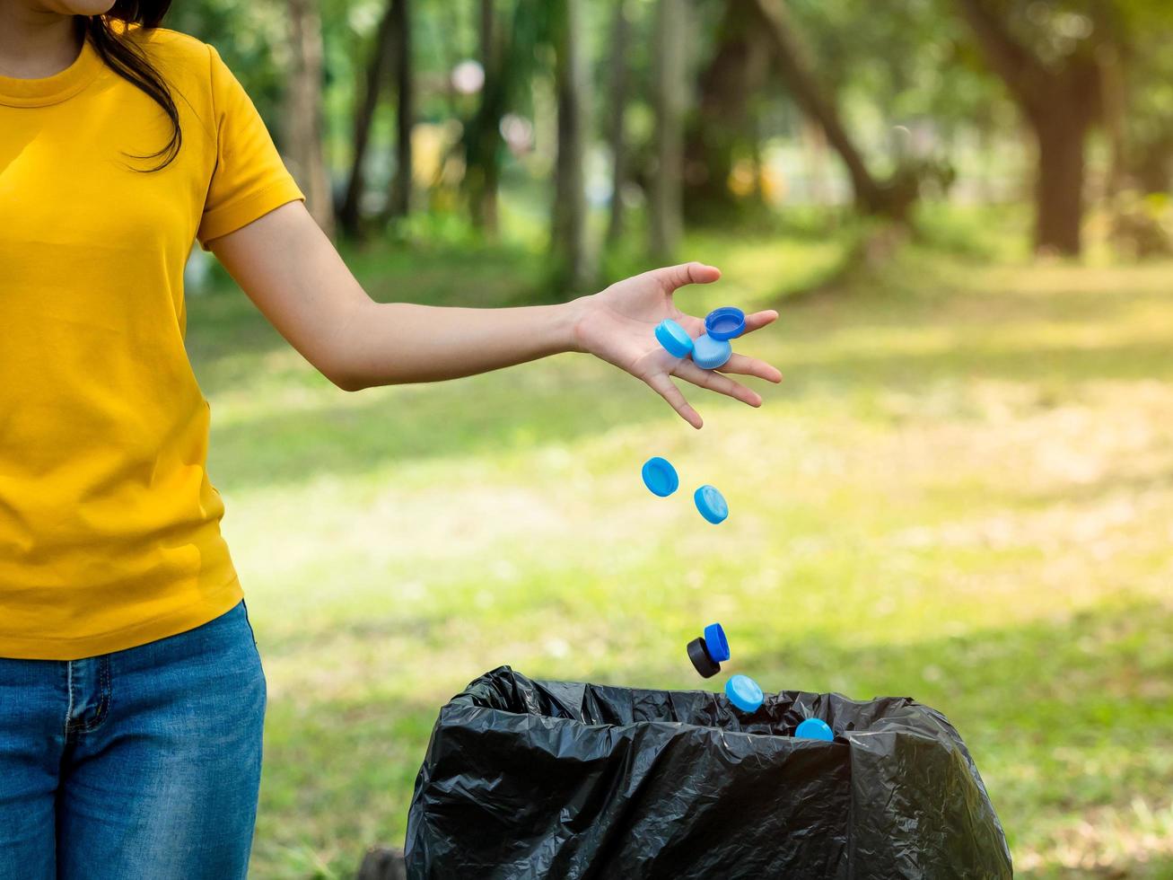 a mulher jogou a tampa da garrafa após o uso no lixo preparado para armazenamento para reciclagem e reutilização foto