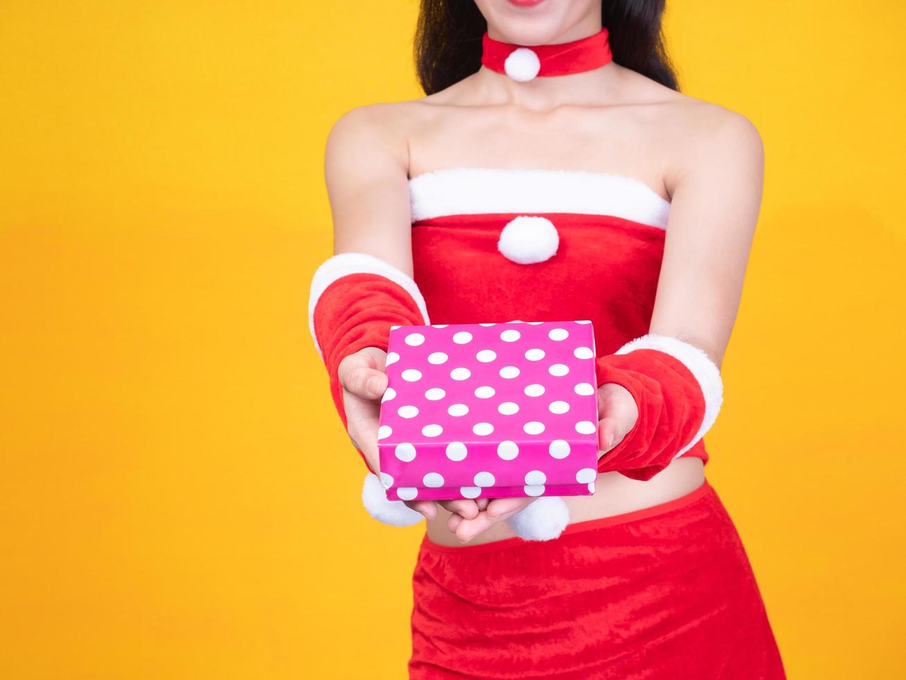 menina asiática em fantasia de papai noel vermelho e caixa de presente no dia da celebração foto